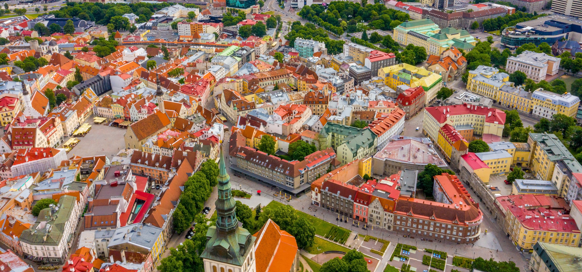 Luftaufnahme der Altstadt von Tallinn mit orangefarbenen Dächern und engen Straßen darunter.
